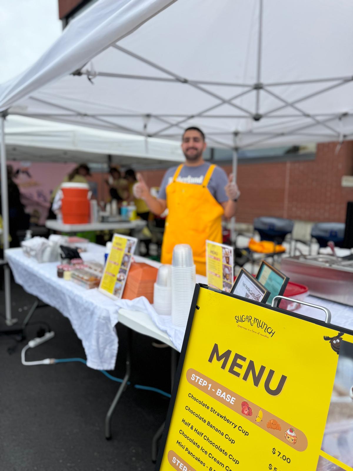 The Sugar Munch booth and yellow menu sign at a market